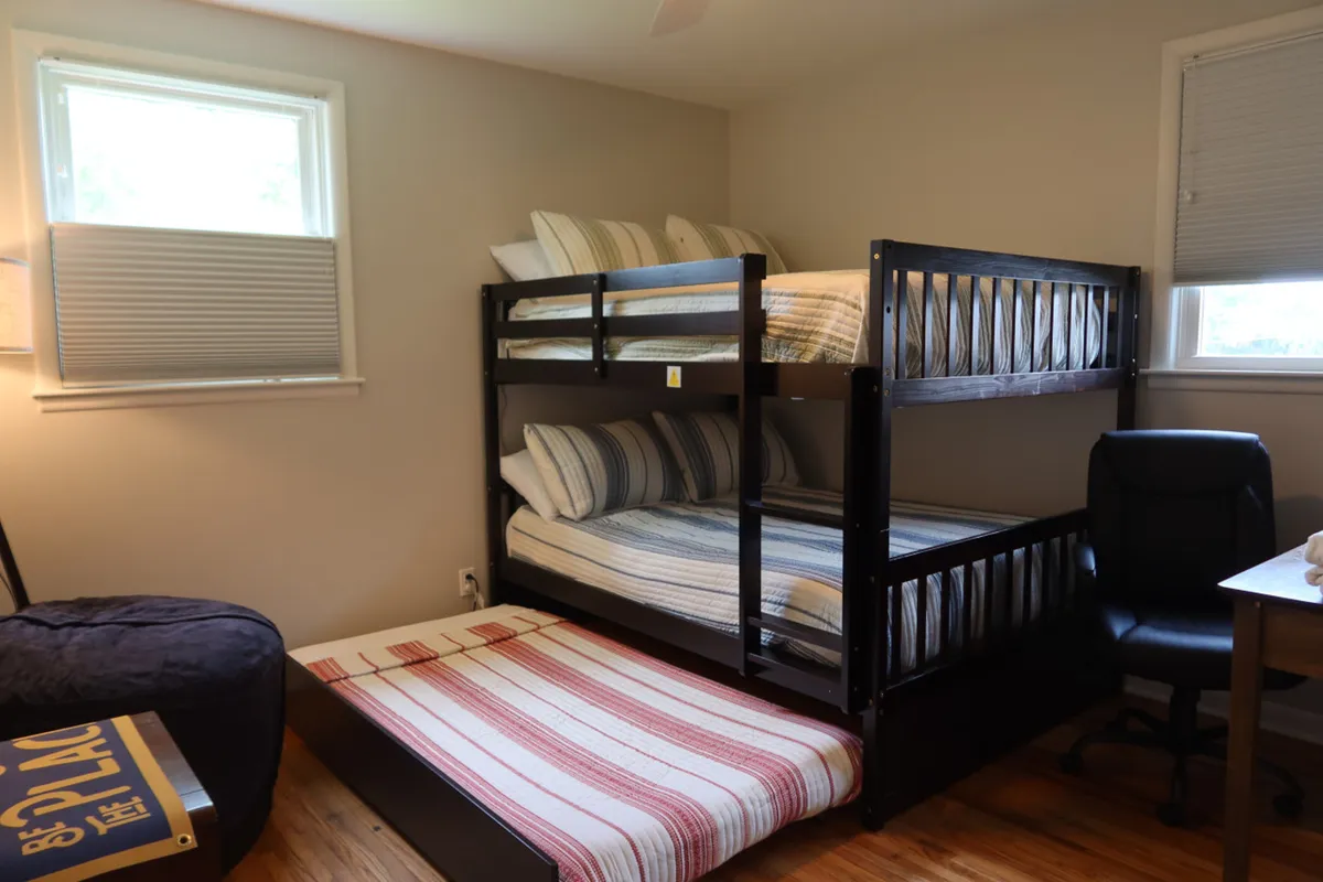A fun and inviting bunk room featuring multiple bunk beds, a bean bag chair for lounging, and a small desk and chair. The space is designed for sleepovers, relaxation, and shared memories, perfect for families or groups traveling together.
