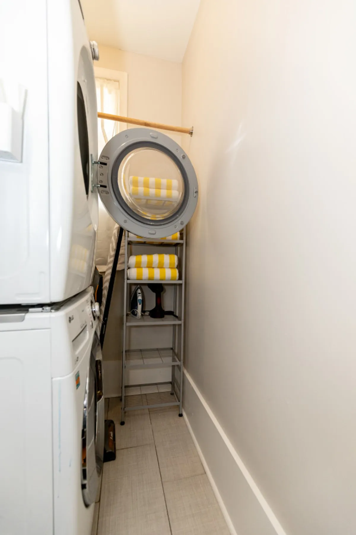 A practical, well-organized laundry area equipped with a washer, dryer, stacked towels, and ironing board. The space is tidy and functional, emphasizing convenience and self-sufficiency.