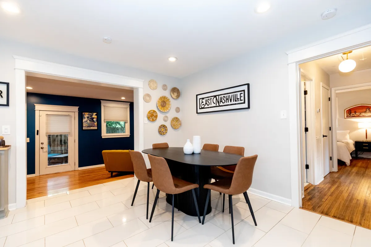 A cozy dining area with a spacious table, decorative wall plates, framed artwork, and a doorway that leads directly to the exterior. The scene is inviting and designed for families or groups to gather, enjoy meals, and plan out daily adventures. The visible connection to the outdoors subtly hints at the home's accessibility to neighborhood attractions.