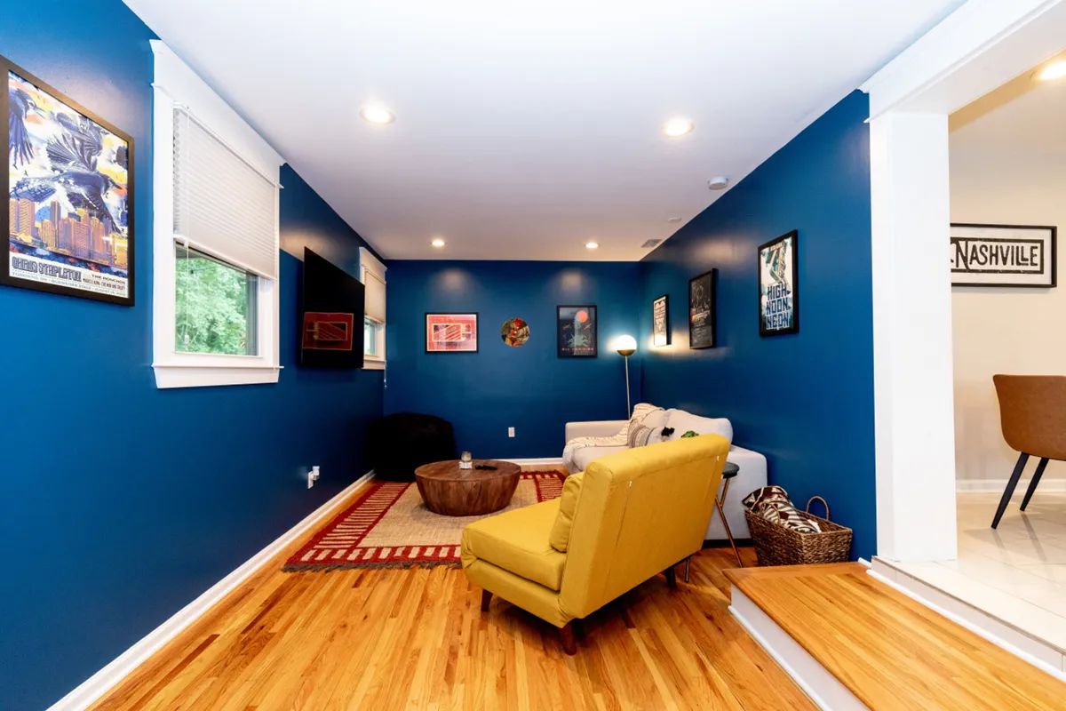 A bright, welcoming living area featuring a yellow armchair, comfortable sofa, coffee table, and wall art. The scene is casual and social, ideal for friends or couples unwinding and reliving the day's adventures.